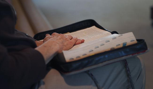 Gail Farnham, longtime parishioner of First Baptist Church, rests her hands on her Bible as she follows along during the sermon given by pastor Ryan Burge in Mt. Vernon, Ill., Sunday, Sept. 10, 2023. (AP Photo/Jessie Wardarski)