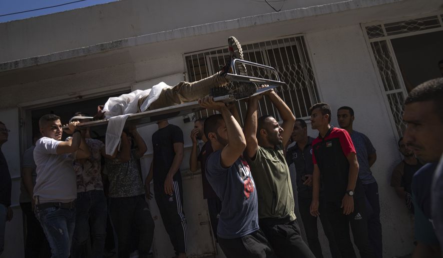 Palestinians carry the body of a man killed during fighting with Israeli forces, in Gaza City, Saturday, Oct. 7, 2023. The militant Hamas rulers of the Gaza Strip carried out an unprecedented, multi-front attack on Israel at daybreak Saturday, firing thousands of rockets as dozens of Hamas fighters infiltrated the heavily fortified border in several locations by air, land, and sea and catching the country off-guard on a major holiday. (AP Photo/Fatima Shbair)