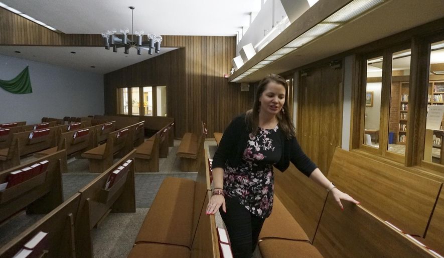 The Rev. Karna Moskalik walks through each line of pews in the sanctuary of Our Savior's Lutheran Church in Stillwater, Minn., on Wednesday Sept. 27, 2023. Lighting a perfumed candle, praying, and meditating are all strategies she employs to ground her and be a more effective faith leader after doing doctoral research on resiliency. (AP Photo/Giovanna Dell'Orto)