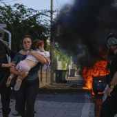 Police officers evacuate a woman and a child from a site hit by a rocket fired from the Gaza Strip, in Ashkelon, southern Israel, Saturday, Oct. 7, 2023. The rockets were fired as Hamas announced a new operation against Israel. (AP Photo/Tsafrir Abayov, File)