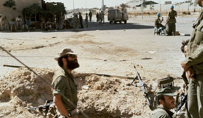 Israeli soldiers dig in at foreground,under the eyes of armed and tense Egyptian troops while in the middle of the street, dividing the two armies is a small United Nations patrol working a makeshift guard station in Suez City, Egypt, Oct. 1973. (AP Photo)