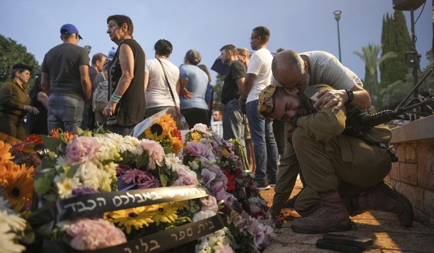 Friends and relatives of Ilai Bar Sade mourn next to his grave during his funeral at the military cemetery in Tel Aviv, Israel, Monday, Oct. 9, 2023. Bar Sade was killed after Hamas militants stormed from the blockaded Gaza Strip into nearby Israeli towns. Israel&#x27;s vaunted military and intelligence apparatus was caught completely off guard, bringing heavy battles to its streets for the first time in decades. (AP Photo/Erik Marmor)