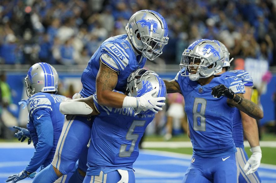 Detroit Lions running back Craig Reynolds (13) is hoisted by running back David Montgomery (5) after his touchdown in the second half of an NFL football game against the Carolina Panthers in Detroit, Sunday, Oct. 8, 2023. The Lions won 42-24. (AP Photo/Carlos Osorio)