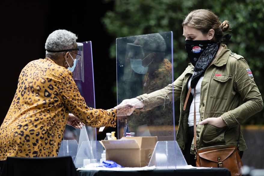 FILE - A voter, right, checks in with an election worker before casting her ballot in the Pennsylvania primary in Philadelphia, Tuesday, June 2, 2020. Counties in Pennsylvania have told Democratic Gov. Josh Shapiro and lawmakers that it is too late to move up the state's 2024 presidential primary date if counties are to successfully administer the election. (AP Photo/Matt Rourke, File)