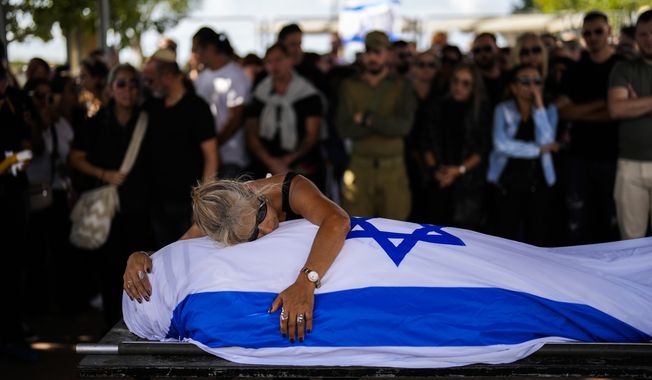 Antonio Mac铆as&#x27; mother cries over her son&#x27;s body covered with the Israeli flag at Pardes Haim cemetery in Kfar Saba, near Tel Aviv, Israel, Sunday, Oct. 15, 2023. Macias was killed by Hamas militants while attending a music festival in southern Israel earlier this month. (AP Photo/Francisco Seco)