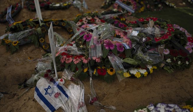 An Israeli flag lies next to flowers on a grave of a soldier killed in Gaza, at Mount Herzl military cemetery, in Jerusalem, on Monday, Oct. 16, 2023. (AP Photo/Petros Giannakouris)