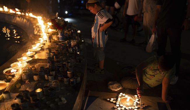 A boy lights candles in the form of the Star of David in honour of victims of the Hamas attacks during a vigil at the Dizengoff square in central Tel Aviv, Israel, on Wednesday, Oct 18, 2023.(AP Photo/Petros Giannakouris)