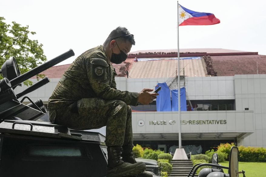 A soldier uses his smartphone on top of an armored personnel carrier as they secure the area where ballot boxes containing the Certificates of Canvass and Election Returns arrive at the House of Representatives in Quezon City, Philippines on May 23, 2022. The Philippine defense chief has ordered all defense personnel and the 163,000-member military to refrain from using online tech tools that use artificial intelligence to generate personal portraits, saying they could pose security risks. (AP Photo/Aaron Favila, File)