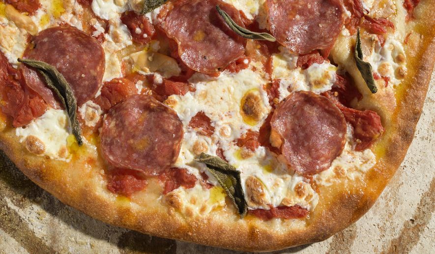 This image released by Milk Street shows a recipe for pizza with salami and smoked mozzarella. (Milk Street via AP)