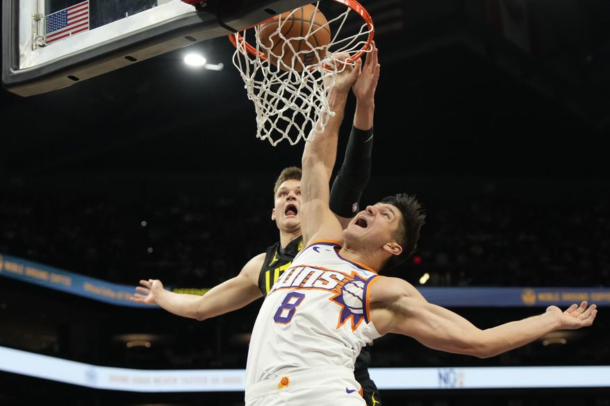 Phoenix Suns guard Grayson Allen (8) dunks against Utah Jazz center Walker Kessler during the second half of an NBA basketball game Saturday, Oct. 28, 2023, in Phoenix. (AP Photo/Rick Scuteri)