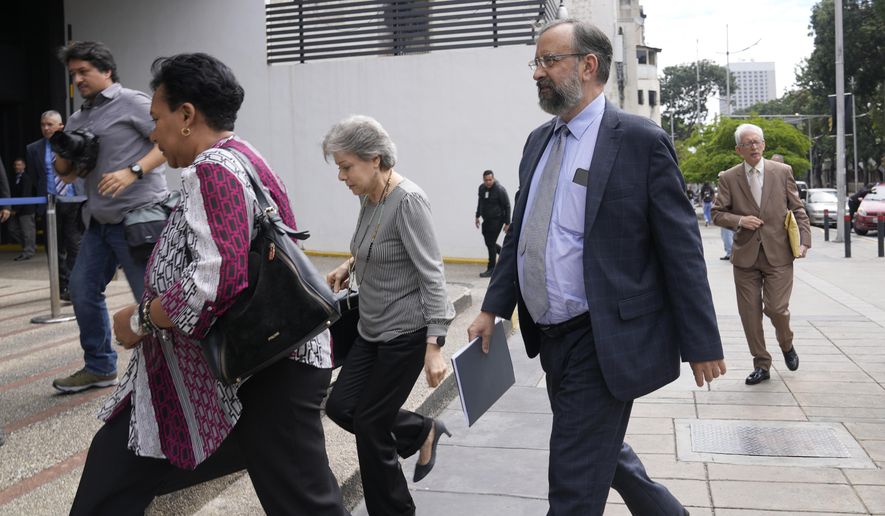 Jesus Maria Casal, president of the Opposition Primary Commission, front right, arrives to the Attorney General's office where he was summoned about the opposition's recent primary elections in Caracas, Venezuela, Monday, Oct. 30, 2023. Prosecutors have opened a criminal investigation into primary organizers on charges including identity fraud and usurping authority and the government has maintained a ban on the primary winner from running for office. (AP Photo/Ariana Cubillos)