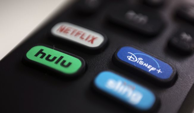 The logos for streaming services Netflix, Hulu, Disney Plus and Sling TV are pictured on a remote control on Aug. 13, 2020, in Portland, Ore. Walt Disney Co. said it will acquire a 33% stake in Hulu from Comcast for approximately $8.6 billion, a deal that will give Disney undisputed control of the streaming service. (AP Photo/Jenny Kane, File)
