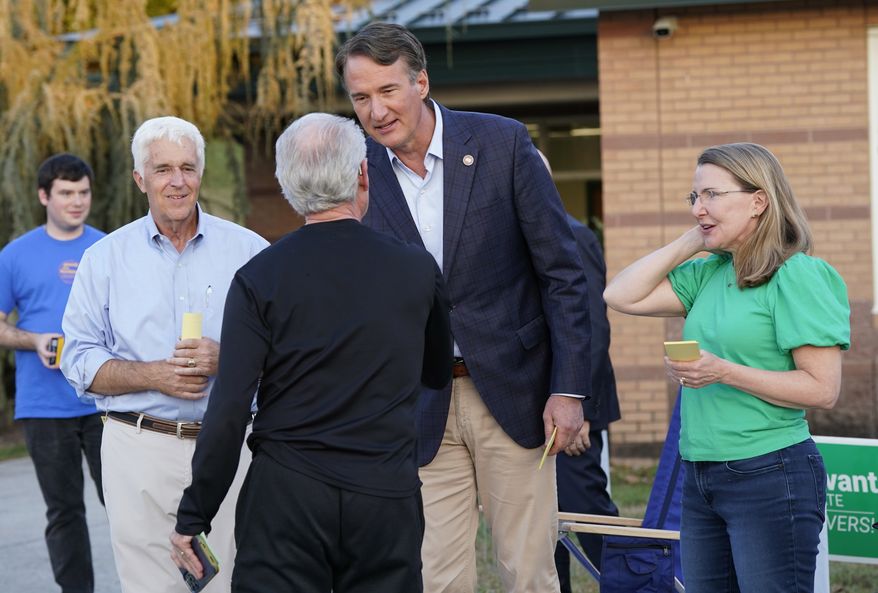 Virginia Gov. Glenn Youngkin, center, hands out sample a ballot to a voter along with Virginia state Sen. Siobhan Dunnavant R-Henrico, right, and Republican candidate for the House of Delegates David Owen, left, as they greet voters at a polling station during Election Day, Tuesday Nov. 7, 2023, in Glenn Allen, Va. (AP Photo/Steve Helber)