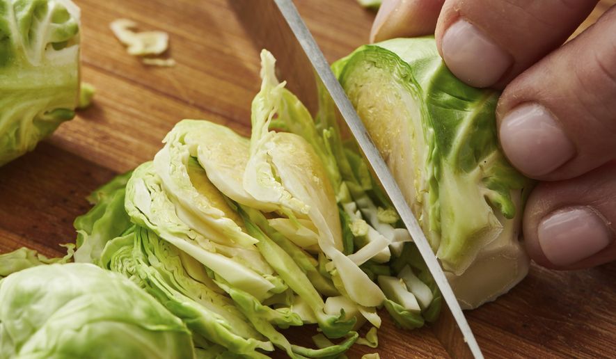 This image provided by Cheyenne Cohen shows Brussel sprouts being sliced on a chopping board. Brussels sprouts are often cooked as a side dish, especially during the cold weather months. They are particularly popular as part of holiday meals such as Thanksgiving and Christmas. And if you think you don't like Brussels sprouts, I'm here to say AP food writer Katie Workman says you just haven't had them prepared well. (Cheyenne Cohen via AP)