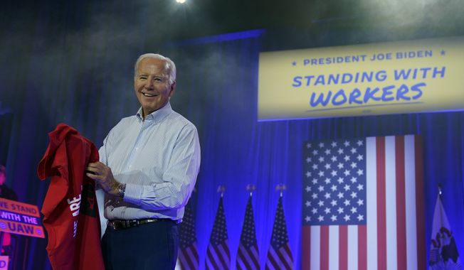 President Joe Biden puts on a UAW Local 1268 shirt before speaking to United Auto Workers at the Community Building Complex of Boone County, Thursday, Nov. 9, 2023, in Belvidere, Ill. (AP Photo/Evan Vucci)
