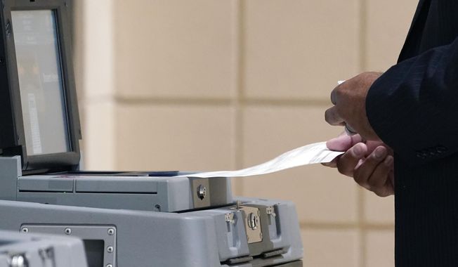 A voter submits a paper ballot into the electronic ballot box at this Jackson, Miss., precinct, Tuesday, Nov. 7, 2023. Statewide offices as well as a number of local and county offices are on the ballot. (AP Photo/Rogelio V. Solis)