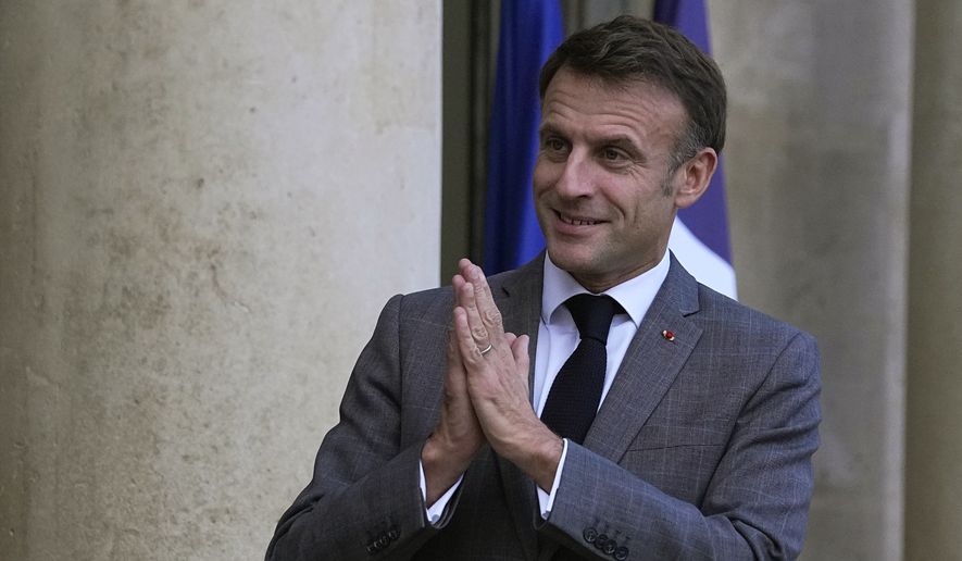 French President Emmanuel Macron greets journalists as he waits for President of Montenegro Jakov Milatovic ahead of the Paris Peace Forum, at the Elysee Palace, in Paris, Thursday, Nov. 9, 2023. The Peace Forum is an annual event involving governments, NGOs and others seeking dialogue around global problems such as climate change, children's exposure to online violence, and threats to human rights. (AP Photo/Michel Euler)