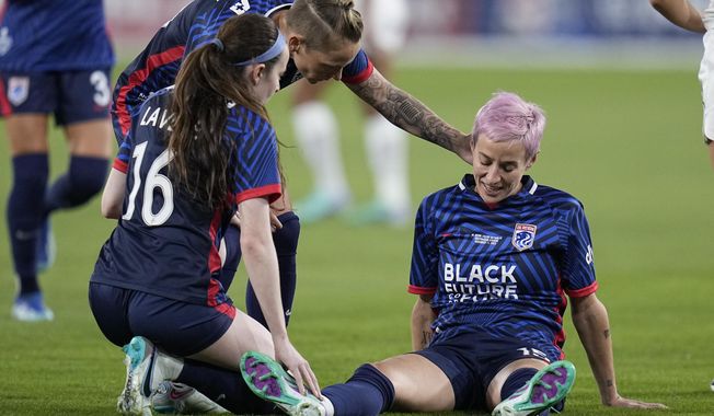 OL Reign forward Megan Rapinoe, right, stays down after an injury as teammates midfielder Rose Lavelle (16) and midfielder Jess Fishlock, center, check on her during the first half of the NWSL Championship soccer game against NJ/NY Gotham, Saturday, Nov. 11, 2023, in San Diego. (AP Photo/Gregory Bull)