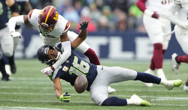 Washington Commanders cornerback Emmanuel Forbes (13) tackles Seattle Seahawks wide receiver Tyler Lockett (16) in the first half of an NFL football game in Seattle, Sunday, Nov. 12, 2023. (AP Photo/Lindsey Wasson)