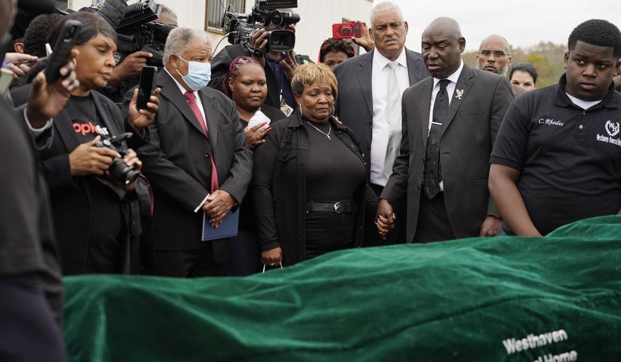 Surrounded by family members and holding hands with civil rights attorney Ben Crump, center right, Bettersten Wade, center, mother of Dexter Wade, a 37-year-old man who died after being hit by a Jackson, Miss., police SUV driven by an off-duty officer, watches her son's body transferred to a mortuary transport in Raymond, Miss. Nov. 13, 2023. An independent pathologist says the deceased Mississippi man had a wallet in the front pocket of the jeans he was buried in that contained his home address. Crump says the finding came from Dr. Frank Peretti’s autopsy report. Peretti was hired to perform an autopsy after Wade’s body was exhumed. (AP Photo/Rogelio V. Solis) **FILE**