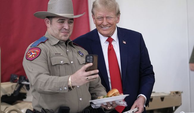 Republican presidential candidate and former President Donald Trump poses for a photo as he helps serve food to Texas National Guard soldiers, troopers and others who will be stationed at the border over Thanksgiving, Sunday, Nov. 19, 2023, in Edinburg, Texas. (AP Photo/Eric Gay)