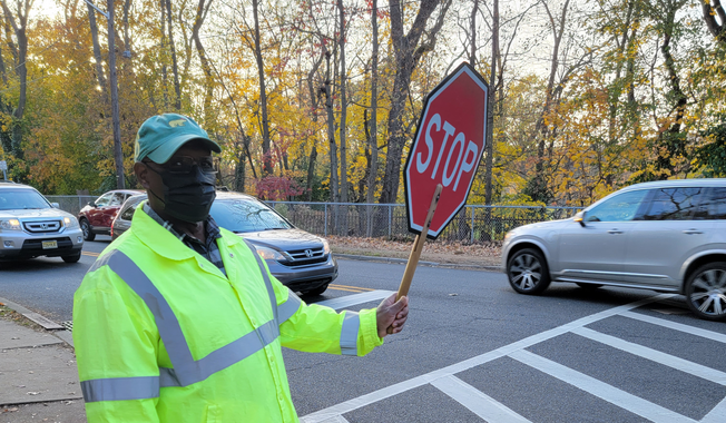 Ray Meeks, a 70-year-old crossing guard, wears a mask daily as he helps school kids get across a busy street in Maplewood, New Jersey. (Tom Howell Jr./The Washington Times)