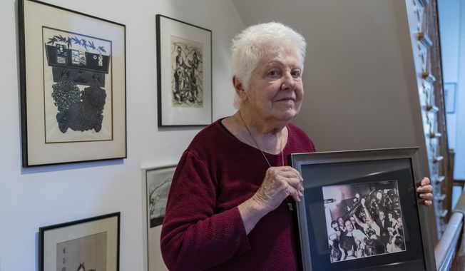 Peggy Simpson holds a photograph of law enforcement carrying Lee Harvey Oswald&#x27;s gun through a hallway packed with reporters, Friday, Nov. 17, 2023, at her home in Washington. Simpson, a former Associated Press reporter, is among the last surviving witnesses to the events surrounding the assassination of Kennedy who are sharing their stories as the nation marks the 60th anniversary. (AP Photo/Jacquelyn Martin)