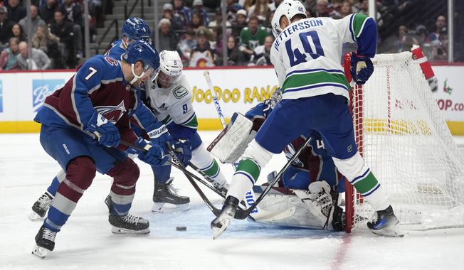 Colorado Avalanche defenseman Devon Toews, front left, vie for control of the puck with defenseman Cale Makar and Vancouver Canucks center J.T. Miller, back left, after Avalanche goaltender Alexandar Georgiev,stopped a shot by Vancouver center Elias Pettersson during the second period of an NHL hockey game Wednesday, Nov. 22, 2023, in Denver. (AP Photo/David Zalubowski)