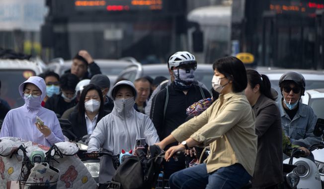 Commuters wear face masks as they wait at an intersection in the central business district during the morning rush hour in Beijing, Friday, May 26, 2023. A surge in respiratory illnesses across China that has drawn the attention of the World Health Organization is caused by the flu and other known pathogens and not by a novel virus, the country&#x27;s health ministry said Sunday. (AP Photo/Mark Schiefelbein, File)