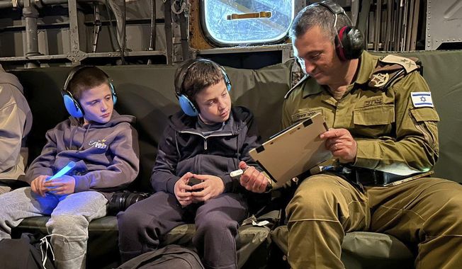 This handout photo provided by the IDF on Monday Nov. 27, 2023, released Israeli hostages Tal Goldstein Almog, 9, left, and his brother Gal, 11 are seen as they return to Israel in an IAF helicopter, after being held hostage by militant group Hamas in the Gaza Strip. (IDF via AP)