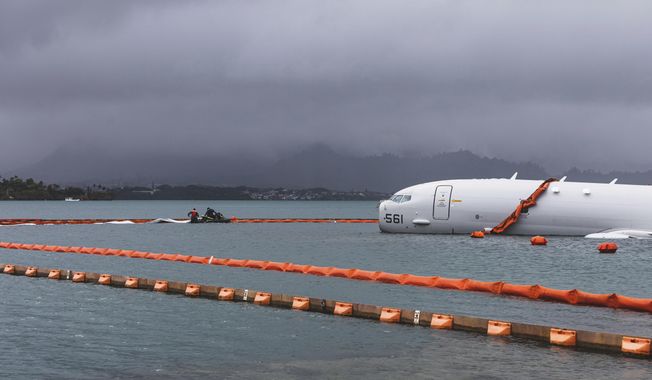 This Nov. 21, 2023, handout photo provided by the U.S. Marine Corps shows U.S. Navy sailors deploying temporary protective barriers around a downed Navy P-8A in waters just off the runway at Marine Corps Air Station Kaneohe Bay in Kaneohe Bay, Hawaii. (U.S. Marine Corps/Sgt. Brandon Aultman via AP)