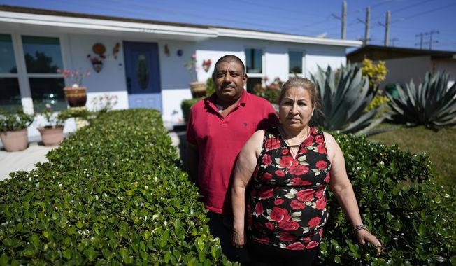 Rosalinda Ramirez, 57, and her partner Jose Guerrero, 41, Mexican immigrants who crossed the border separately over two decades ago and who have built lives and he a landscaping business in the U.S. but never found a route to obtain legal status, pose for a picture outside their home in Homestead, Fla., Tuesday, Nov. 7, 2023. The couple are among those longterm immigrants in the U.S. who are frustrated to see newer arrivals getting work permits and government assistance, while they have paid taxes for decades without earning work permits, the ability to visit relatives back home and return, or freedom from the fear of deportation. (AP Photo/Rebecca Blackwell)