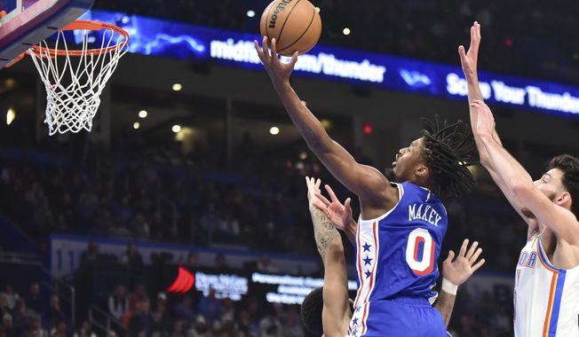 Philadelphia 76ers guard Tyrese Maxey, right, goes up for a shot over Oklahoma CIty Thunder forward Kenrich Williams, left, in the first half of an NBA basketball game, Saturday, Nov. 25, 2023, in Oklahoma City. (AP Photo/Kyle Phillips)