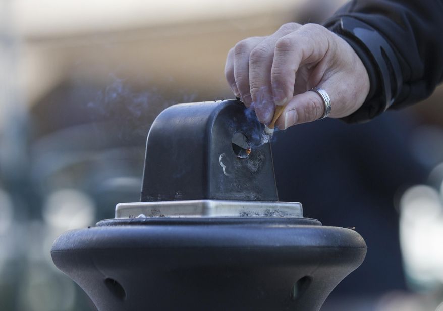 A man stubs out a cigarette in a public ashtray in Paris, France, on Oct. 1, 2015. France will ban smoking on all beaches, public parks, forests and some other public areas as part of a national anti-tobacco plan detailed by the health minister on Tuesday Nov. 28, 2023. (AP Photo/Jacques Brinon, File)