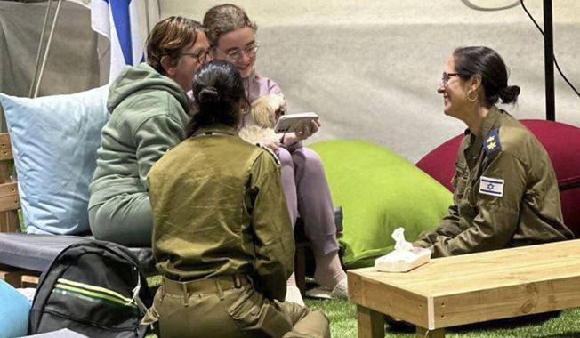 This handout photo provided by GPO shows Gabriela and Mia Leimberg, rear, talking with family from a meeting point in Israeli territory after being released by Hamas, Tuesday, Nov. 28, 2023. (GPO/Handout via AP)