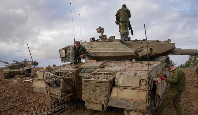 Israeli soldiers work on a tank at an army staging area near Israel&#x27;s border with Gaza, southern Israel, Monday, Nov. 27, 2023. on the fourth day of a temporary cease-fire between Israel and Hamas. (AP Photo/Ohad Zwigenberg)