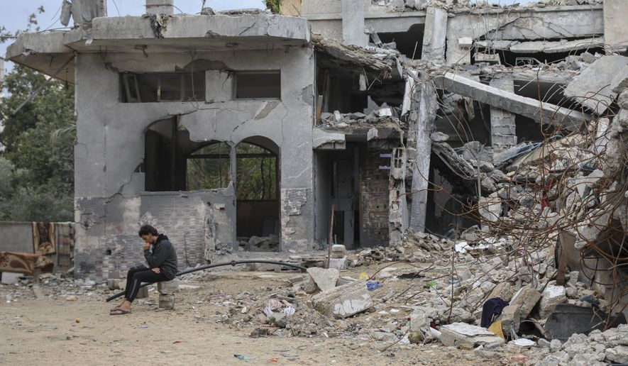 A Palestinian man sits on the rubble of his relative destroyed building in Jebaliya, Gaza Strip, Tuesday, Nov. 28, 2023, on the fifth day of the temporary ceasefire between Hamas and Israel. (AP Photo/Mohammed Hajjar)