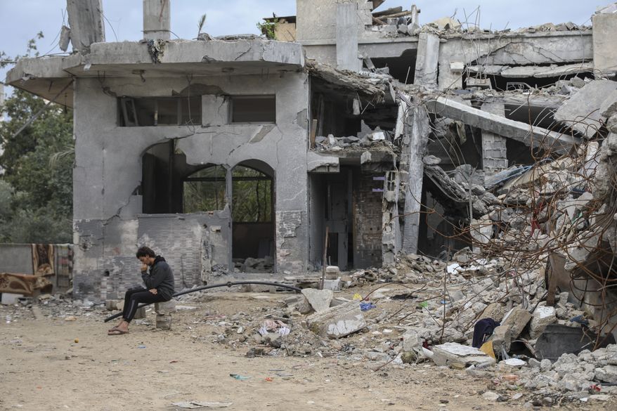A Palestinian man sits on the rubble of his relative destroyed building in Jebaliya, Gaza Strip, Tuesday, Nov. 28, 2023, on the fifth day of the temporary ceasefire between Hamas and Israel. (AP Photo/Mohammed Hajjar)
