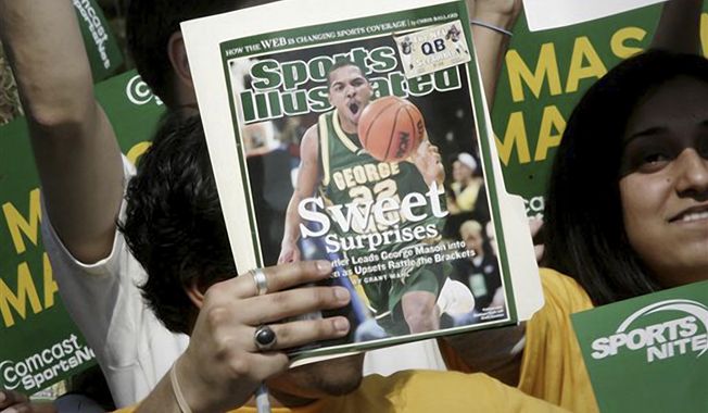 A George Mason University fan holds up a Sports Illustrated magazine at a send off for the team, March 29, 2006, in Fairfax, Va. Sports Illustrated is the latest media company damaged by being less than forthcoming about who or what is writing its stories. The website Futurism reported that the once-grand magazine used articles with 鈥渁uthors鈥� who apparently don&#x27;t exist, with photos generated by AI. The magazine denied claims that some articles themselves were AI-assisted, but has cut ties with a vendor it hired to produce the articles. (AP Photo/Lawrence Jackson, File)