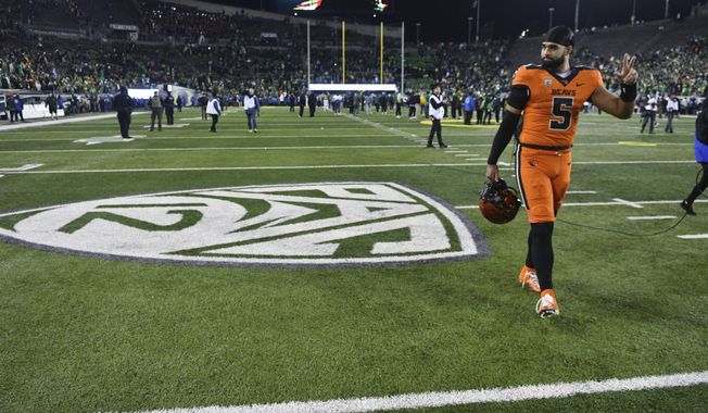 Oregon State quarterback DJ Uiagalelei (5) walks by the Pac-12 logo and waves to fans after the team&#x27;s NCAA college football game against Oregon, Friday, Nov. 24, 2023, in Eugene, Ore. This was the final Pac-12 football game for the team. (AP Photo/Mark Ylen)