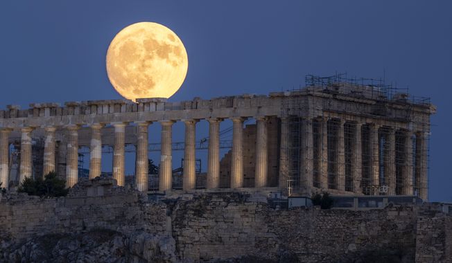 The moon rises in the sky behind the 5th century B.C. Parthenon temple at the ancient Acropolis hill, in Athens, July 31, 2023. The Parthenon Sculptures have been displayed in London for more than 200 years. But Greece vocally wants them back. Diplomacy failed when U.K. Prime Minister Rishi Sunak abruptly called off a London meeting scheduled for Tuesday Nov. 28, 2023 with Greek counterpart Kyriakos Mitsotakis. (AP Photo/Petros Giannakouris, File)