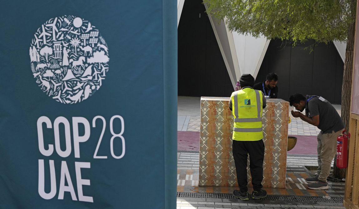 A worker drinks water, right, ahead of the COP28 U.N. Climate Summit, Wednesday, Nov. 29, 2023, in Dubai, United Arab Emirates. (AP Photo/Rafiq Maqbool)