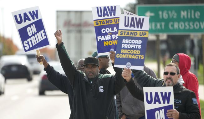 United Auto Workers members walk the picket line during a strike at the Stellantis Sterling Heights Assembly Plant, in Sterling Heights, Mich., Monday, Oct. 23, 2023. A six-week United Auto Workers strike at Ford cut sales by about 100,000 vehicles and cost the company $1.7 billion in lost profits this year, Ford said Thursday, Nov. 30, 2023. (AP Photo/Paul Sancya, File)