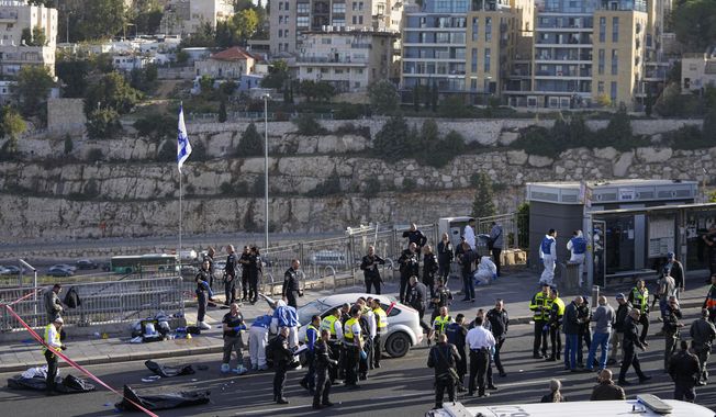 Israeli police officer and volunteers from the Zaka rescue service work at the shooting attack in Jerusalem, Thursday, Nov. 30, 2023. Police said gunmen opened fire Thursday on people waiting for buses and rides where a main highway enters Jerusalem from Tel Aviv. The attack left one dead, one in critical condition and five others wounded, according to Magen David Adom, Israel&#x27;s national emergency medical, disaster, ambulance and blood bank service. Two attackers were killed, police said. (AP Photo/Ohad Zwigenberg)