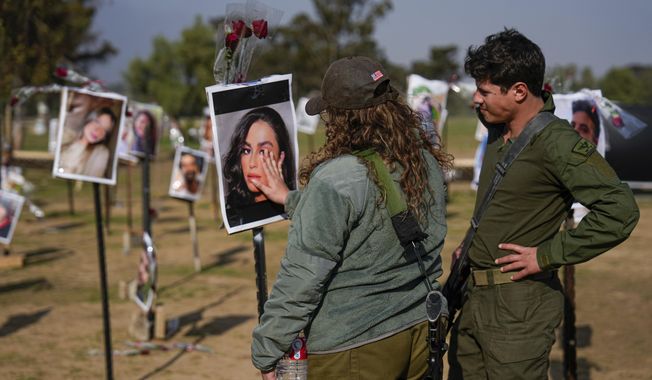 Israeli soldiers look at photos of people killed and taken captive by Hamas militants during their violent rampage through the Nova music festival in southern Israel, which are displayed at the site of the event, to commemorate the October 7, massacre, near kibbutz Re&#x27;im, Friday, Dec. 1, 2023. (AP Photo/Ariel Schalit)