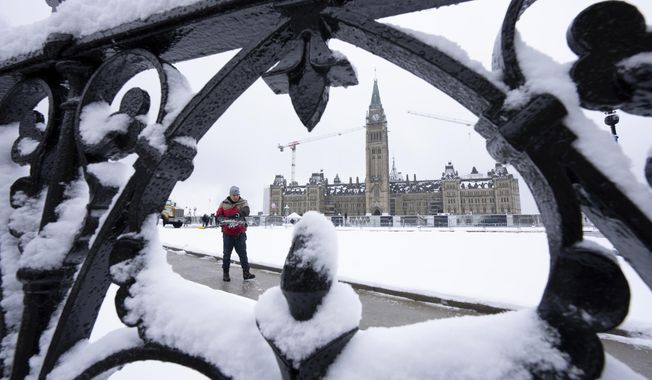 A worker prepares a pathway on Parliament Hill following a snow fall, Monday, Dec. 4, 2023., in Ottawa, Ontario. (Adrian Wyld/The Canadian Press via AP)
