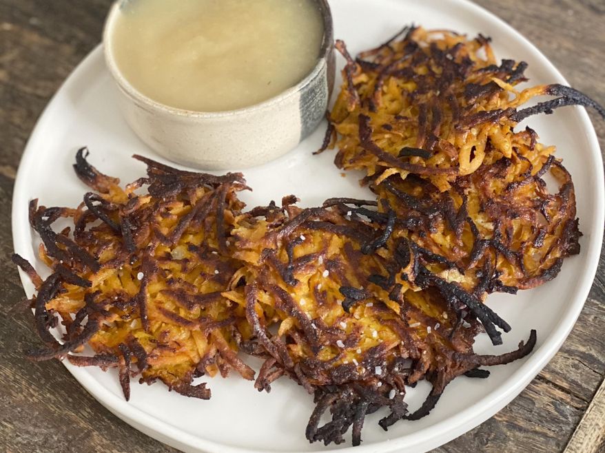 This image provided by Katie Workman shows apple sauce and ginger sweet potato pancakes. Traditional Hanukkah latkes are pancakes made from white potatoes and simply seasoned with salt, pepper and onion. But nowhere is it written that you can't play around with that. AP food writer Katie Workman suggests a recipe for ginger sweet potato pancakes as a variation on traditional latkes. (Katie Workman via AP)