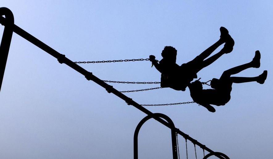 Children play on swings during National Night Out, Tuesday, August 1, 2023, in Salisbury, Md. A Delaware school district will reimburse the family of a Jewish student for counseling and issue an anti-harassment statement after a federal probe found the girl was targeted and bullied over her religious identity. (AP Photo/Julia Nikhinson)