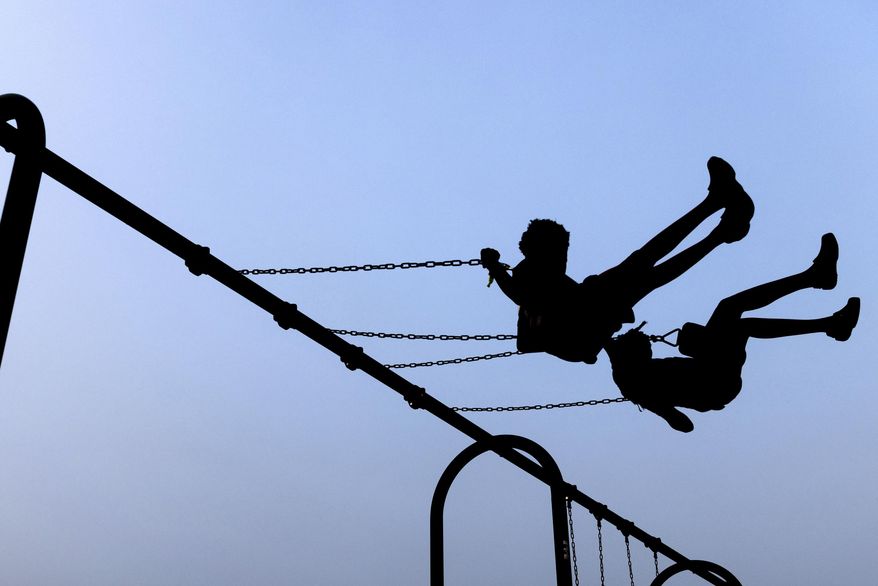 Children play on swings during National Night Out, Tuesday, August 1, 2023, in Salisbury, Md. A Delaware school district will reimburse the family of a Jewish student for counseling and issue an anti-harassment statement after a federal probe found the girl was targeted and bullied over her religious identity. (AP Photo/Julia Nikhinson)