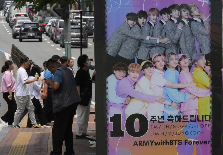 A poster showing K-pop band BTS members is displayed to celebrate its 10th debut anniversary at a bus station in Seoul, South Korea on June 14, 2023. Four more members of the K-pop supergroup BTS are to begin their mandatory South Korean military duties soon, their management agency said. (AP Photo/Ahn Young-joon, File)